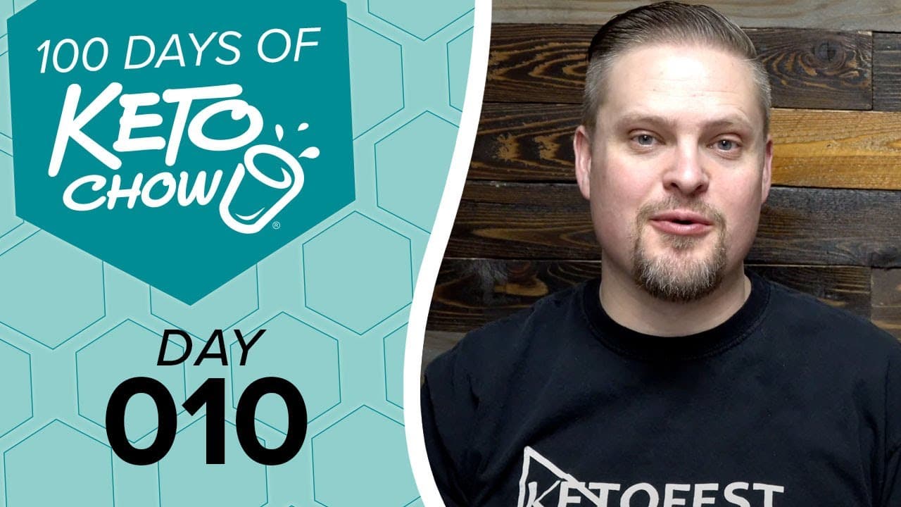 Promotional graphic with KETO CHOW logo and text 100 DAYS OF KETO CHOW, DAY 010, on a teal honeycomb background. A man wears a black KETOFEST t-shirt against a wooden wall.