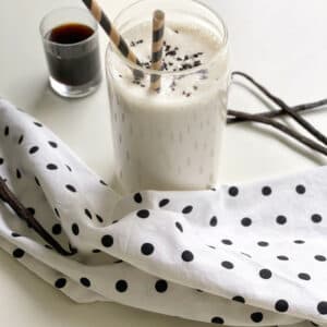 Vanilla keto chow shake in a clear glass with two striped straws.