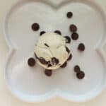 Top view-cookie dough ball on a white plate sprinkled with chocolate chips