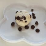 Cookie dough ball on a white plate sprinkled with chocolate chips