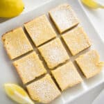 White plate filled with Lemon Bars, dusted with powdered erythritol. Lemon wedges on the side.