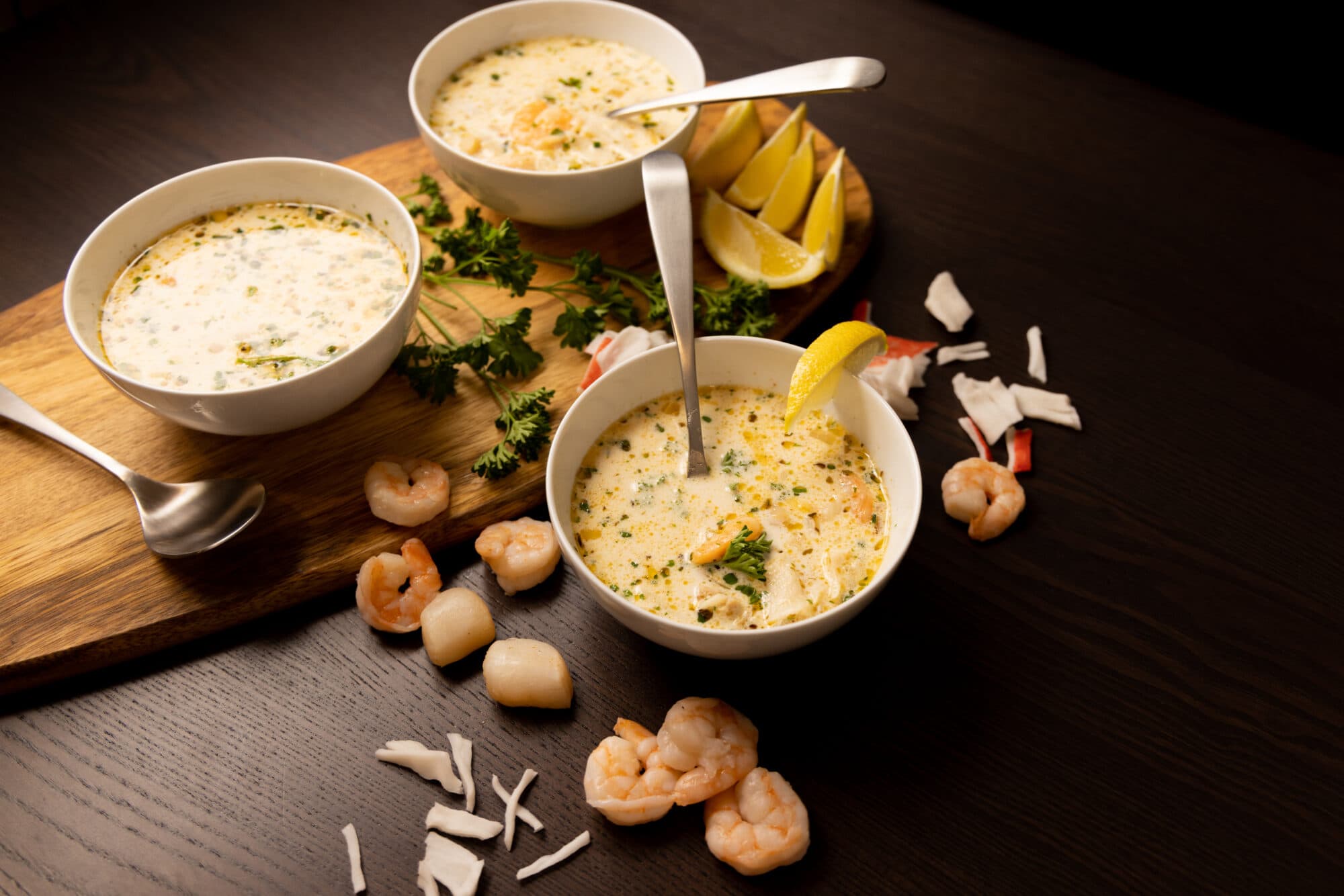 Three white bowls filled with Seafood Bisque. Lemon wedges and shrimp on the side.
