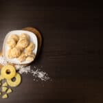 Top view - White plate filled with Coconut Macaroons. Sliced pineapple on the side.