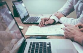 Closeup of desk with coworkers working on research together for keto research roundup article