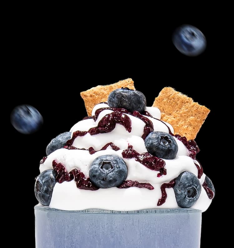 A blue shake topped with whipped cream and blue berries.