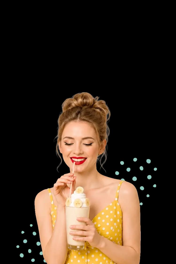 A smiling woman drinking a Banana Keto Chow shake.