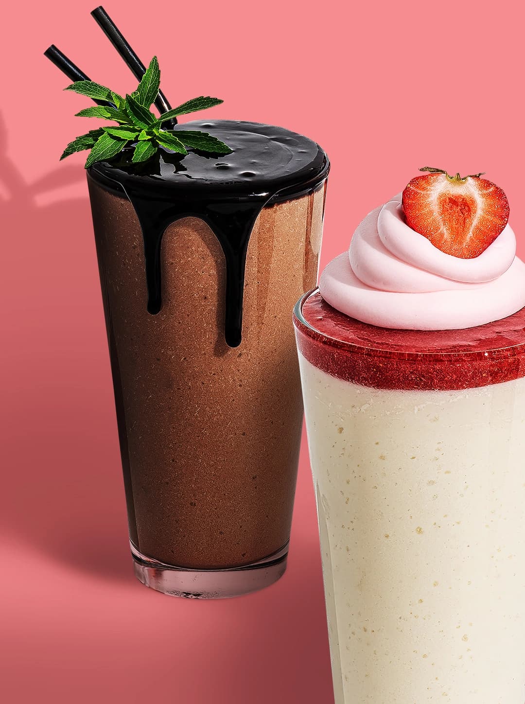Two tall Keto Chow shakes in front of a coral-pink background—one chocolate shake topped with chocolate syrup, mint leaves, and black straws; the other a vanilla shake with strawberry puree, swirled pink whipped topping, and half a strawberry.