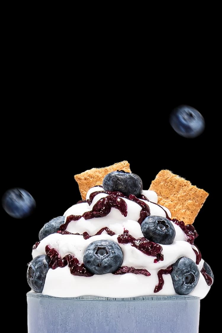 A blue shake topped with whipped cream and blue berries.