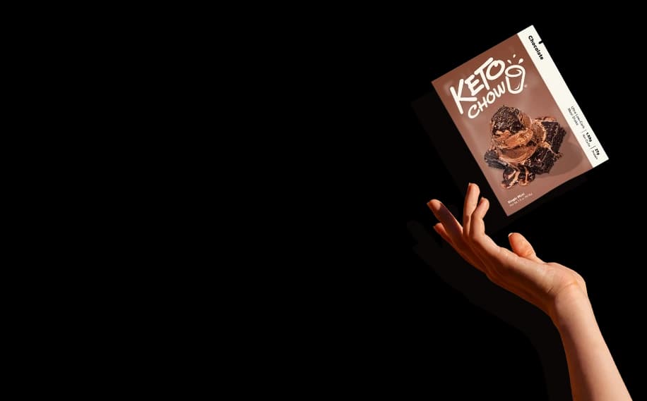 A hand throwing a single pack of Chocolate Keto Chow.